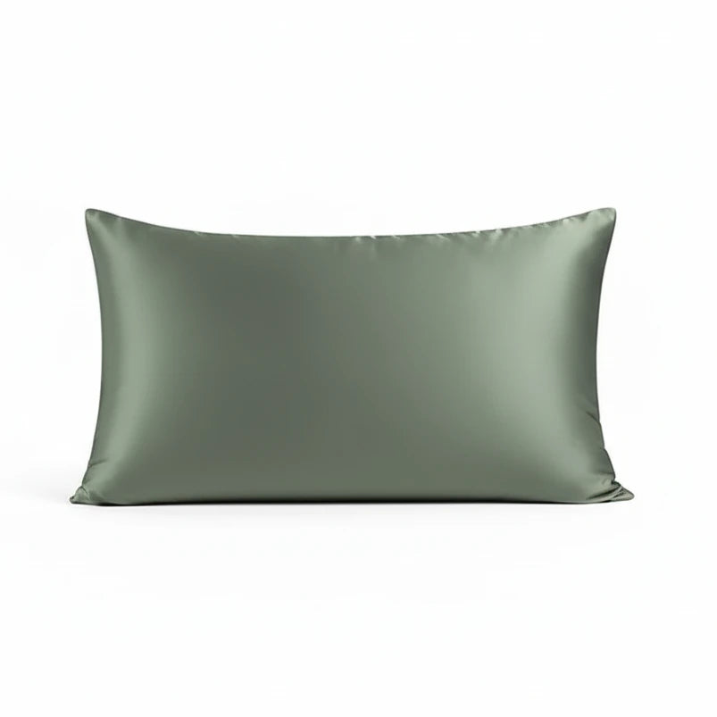 Two green satin pillows on a textured dark surface with a geometric pattern.